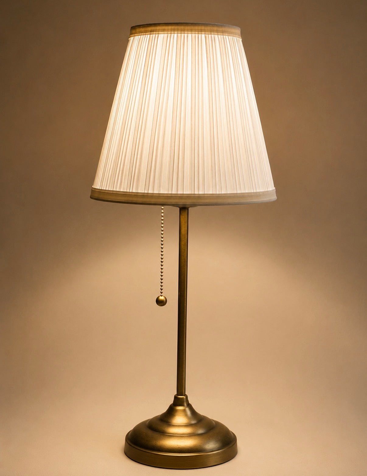 Table lamp with pleated white shade on a beige background
